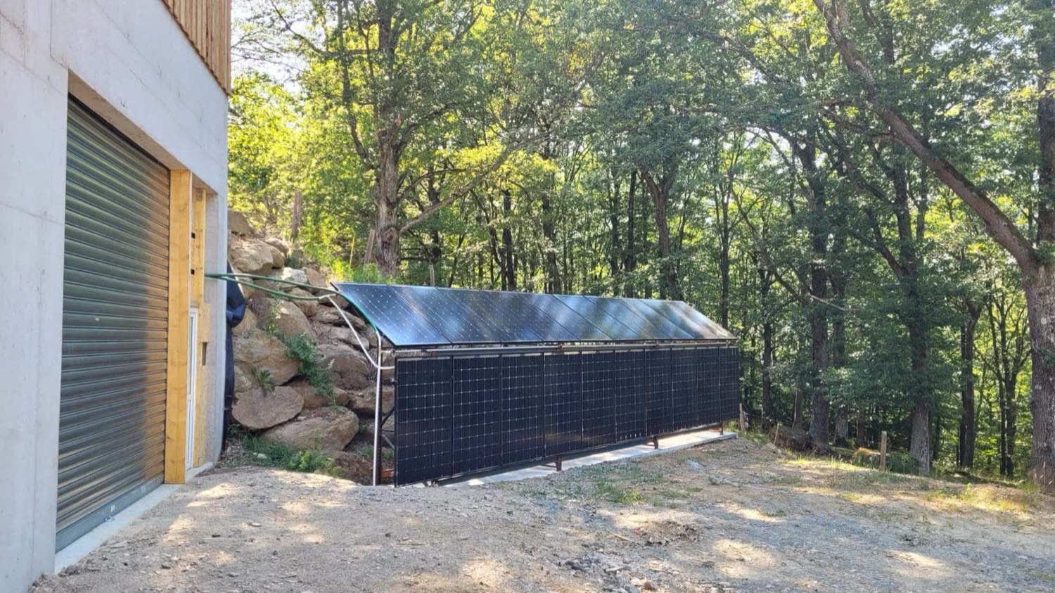 Capteurs solaires à air alignés au sol devant un hangar agricole